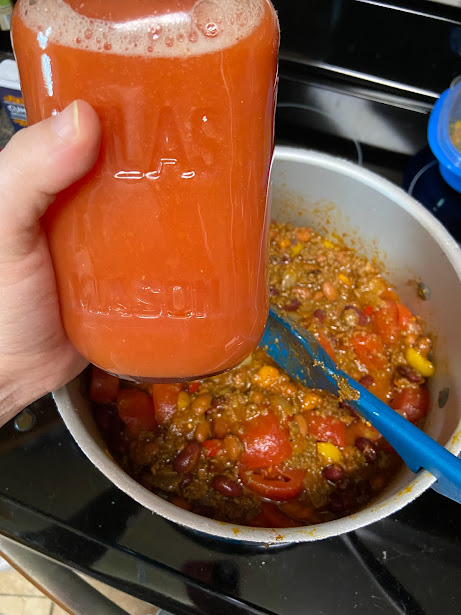 tomato juice jar adding to chili pot