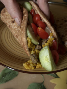 Mediterranean lamb bowl stuffed inside pita with tomatoes, cucumbers, turmeric rice, and tzatziki 