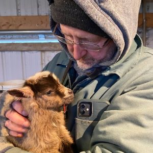 man holding baby goat